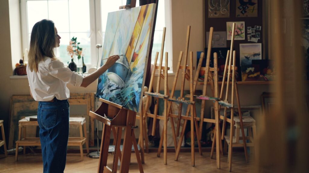 Kvinde maler et farverigt maleri i et lyst atelier